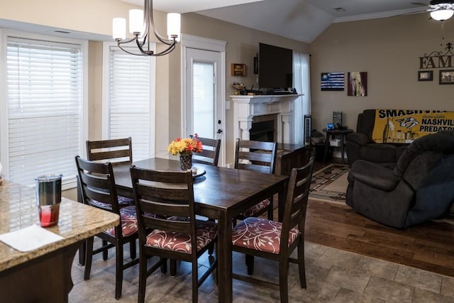 dining space featuring ceiling fan with notable chandelier and vaulted ceiling