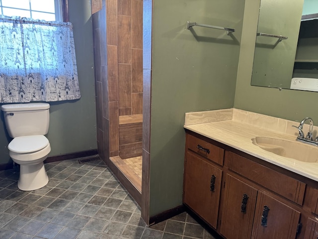 bathroom with tiled shower, vanity, toilet, and tile patterned floors