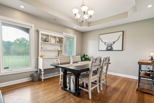 dining area featuring an inviting chandelier, hardwood / wood-style floors, and a raised ceiling