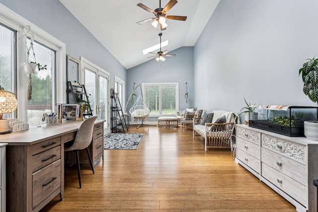 home office featuring ceiling fan, built in desk, high vaulted ceiling, and light hardwood / wood-style flooring