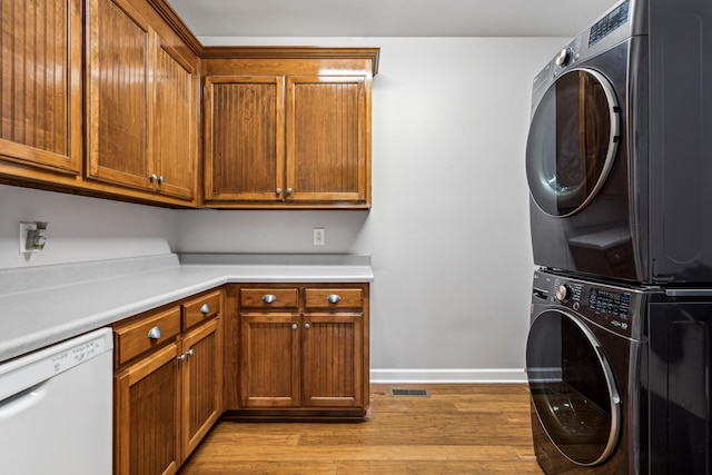 laundry room featuring stacked washer and clothes dryer and light wood-type flooring