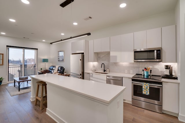 kitchen featuring stainless steel appliances, hanging light fixtures, sink, and white cabinets