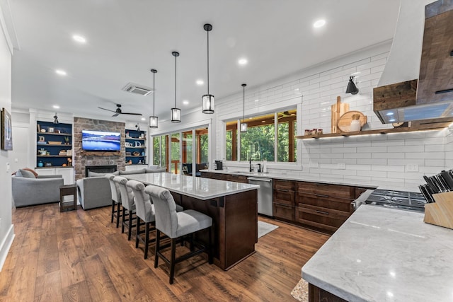 kitchen with decorative light fixtures, dishwasher, a breakfast bar area, a large island, and light stone countertops