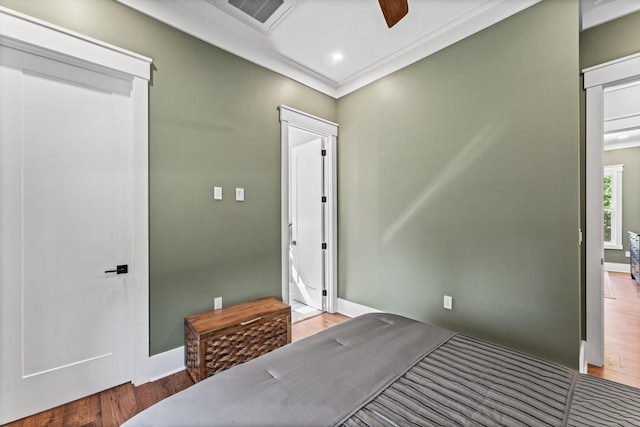 bedroom featuring ceiling fan, ornamental molding, and wood-type flooring