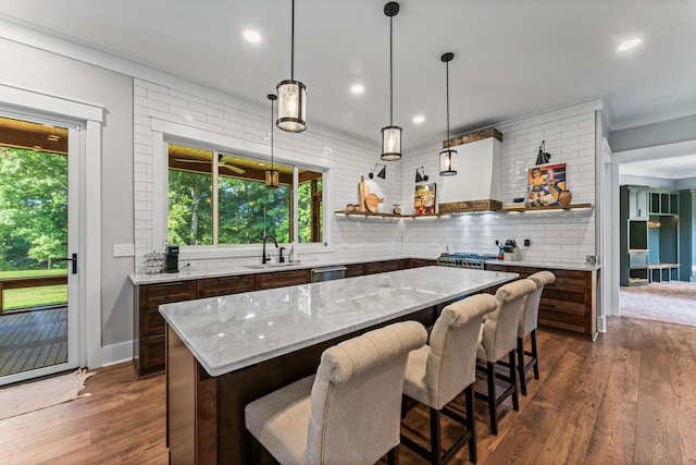 kitchen featuring pendant lighting, sink, backsplash, dark hardwood / wood-style flooring, and a center island