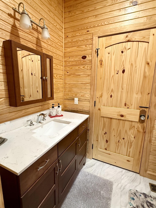 bathroom featuring visible vents, vanity, and wooden walls