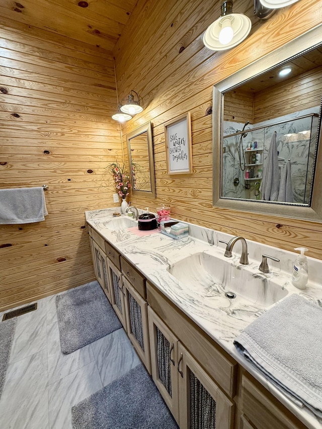 bathroom featuring visible vents, a sink, a marble finish shower, and double vanity