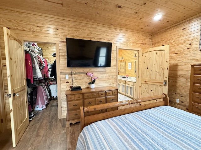 bedroom featuring a walk in closet, a closet, wood walls, wood finished floors, and wooden ceiling