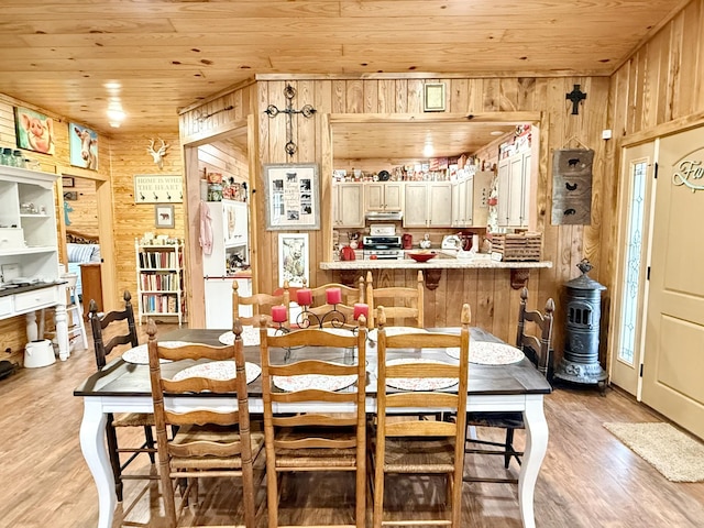 dining space with wooden ceiling, wooden walls, and light wood-style floors