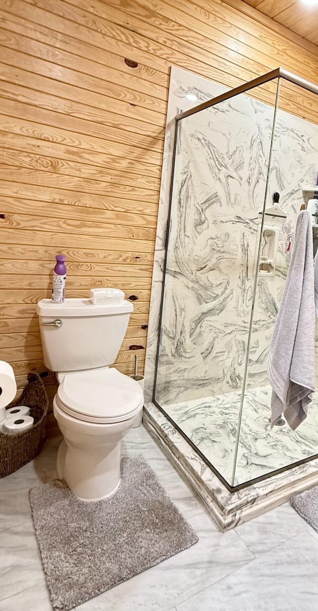 bathroom featuring a marble finish shower, wood walls, and toilet