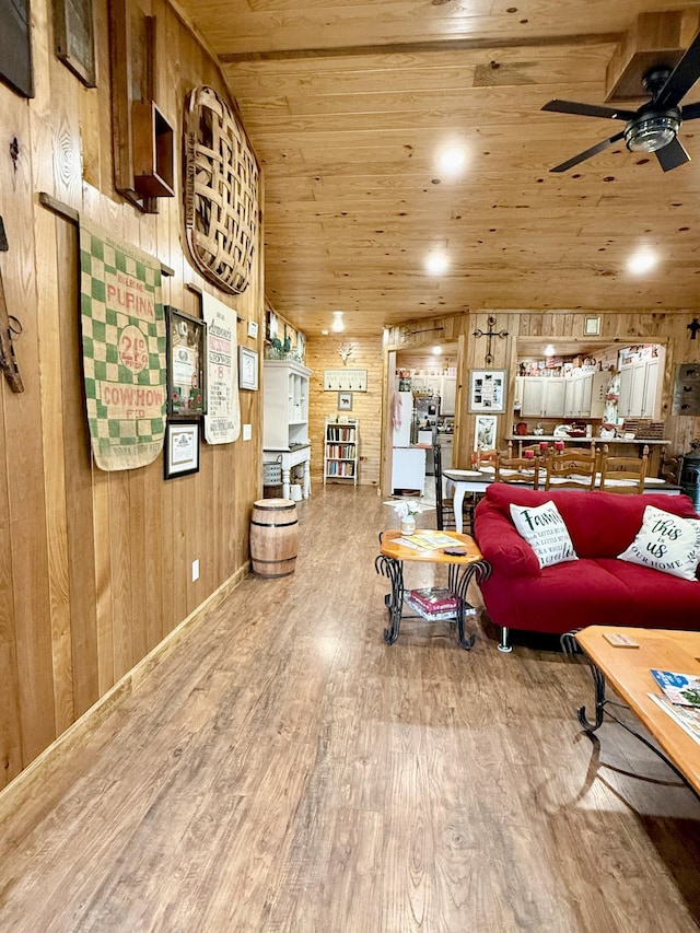 living area featuring ceiling fan, wood walls, vaulted ceiling, wood finished floors, and wooden ceiling