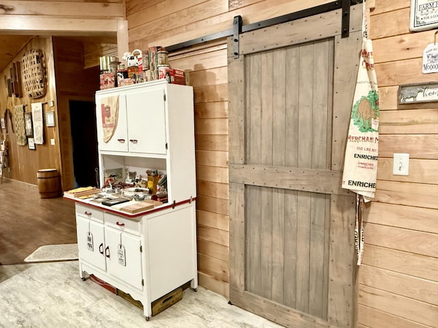 interior space featuring a barn door, white cabinetry, and wooden walls