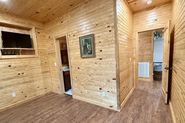 spare room with wooden ceiling, wooden walls, visible vents, and wood finished floors