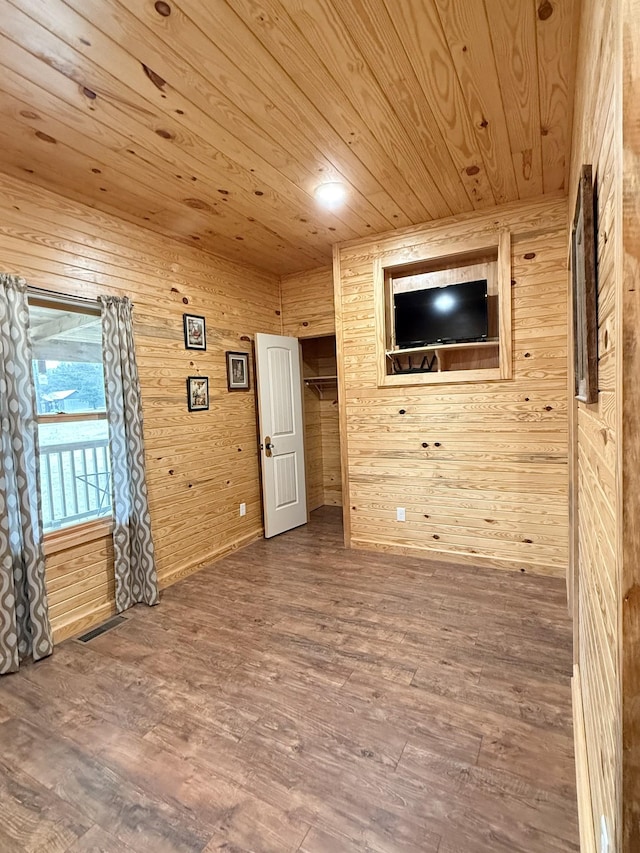 unfurnished room featuring visible vents, wood finished floors, wood ceiling, and wooden walls