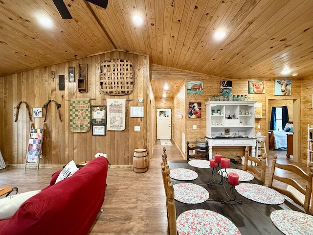 dining space featuring lofted ceiling, wood finished floors, wood ceiling, and wooden walls