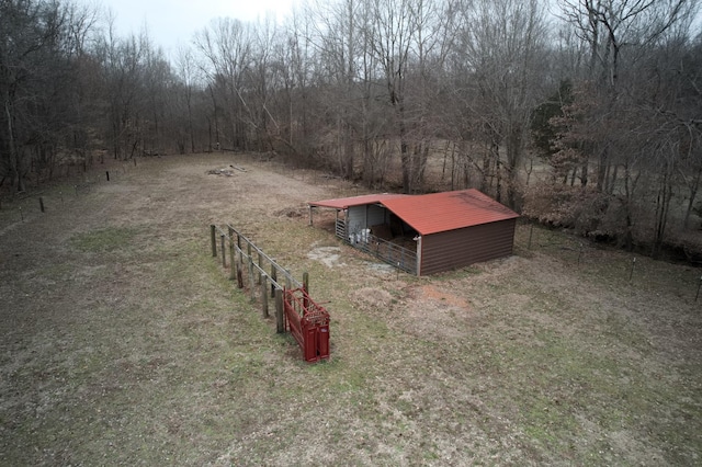 view of yard featuring an outbuilding, a pole building, fence, and a view of trees