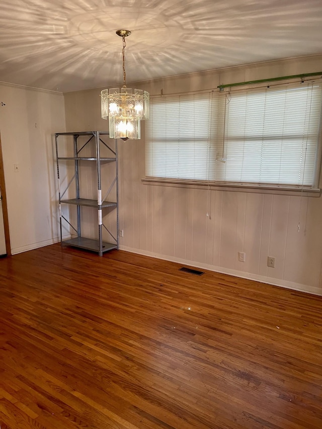 unfurnished dining area featuring an inviting chandelier and dark hardwood / wood-style floors