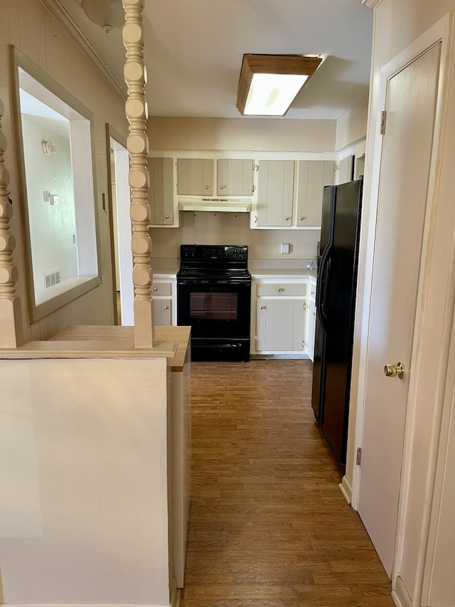 kitchen with dark hardwood / wood-style flooring, ornamental molding, black appliances, and kitchen peninsula