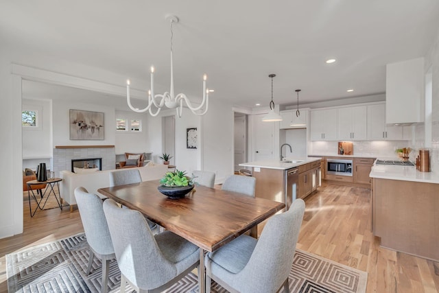 dining area with sink, a notable chandelier, and light hardwood / wood-style floors