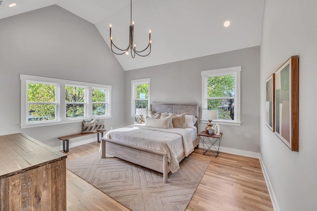 bedroom featuring multiple windows, high vaulted ceiling, an inviting chandelier, and light wood-type flooring