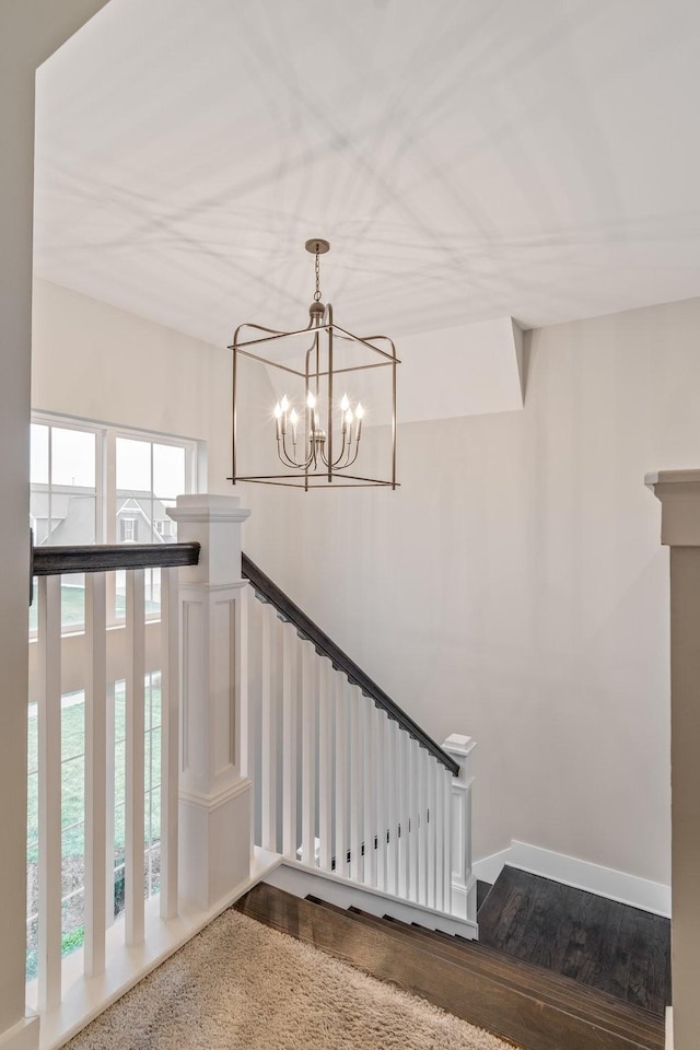 staircase with a notable chandelier and wood-type flooring