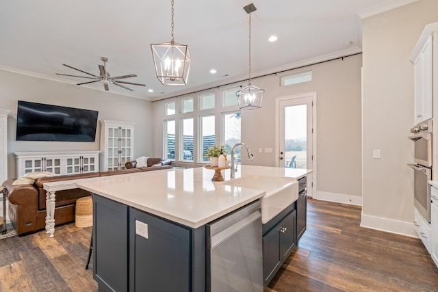 kitchen featuring sink, decorative light fixtures, a center island with sink, stainless steel appliances, and white cabinets