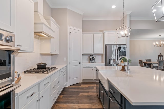 kitchen with appliances with stainless steel finishes, custom range hood, pendant lighting, and white cabinets