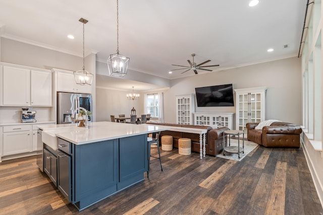 kitchen featuring a kitchen island with sink, stainless steel fridge with ice dispenser, hanging light fixtures, and white cabinets