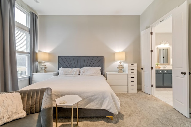 bedroom featuring ensuite bath and light colored carpet