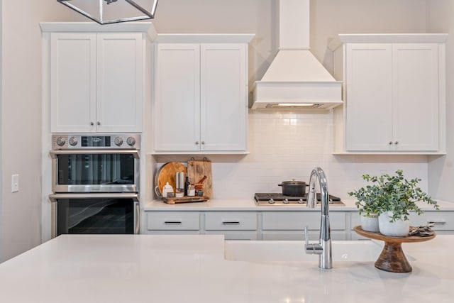 kitchen featuring custom exhaust hood, white cabinetry, and stainless steel appliances