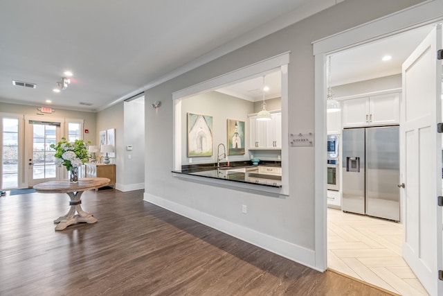 interior space featuring sink, white cabinetry, ornamental molding, appliances with stainless steel finishes, and pendant lighting