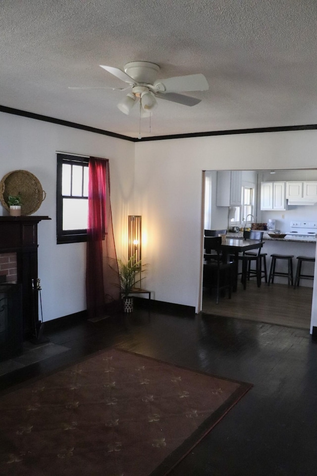 living room featuring ceiling fan, ornamental molding, and a textured ceiling