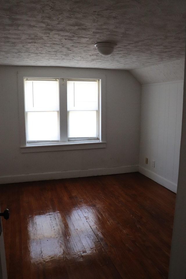 bonus room featuring lofted ceiling, dark wood-type flooring, a textured ceiling, and plenty of natural light