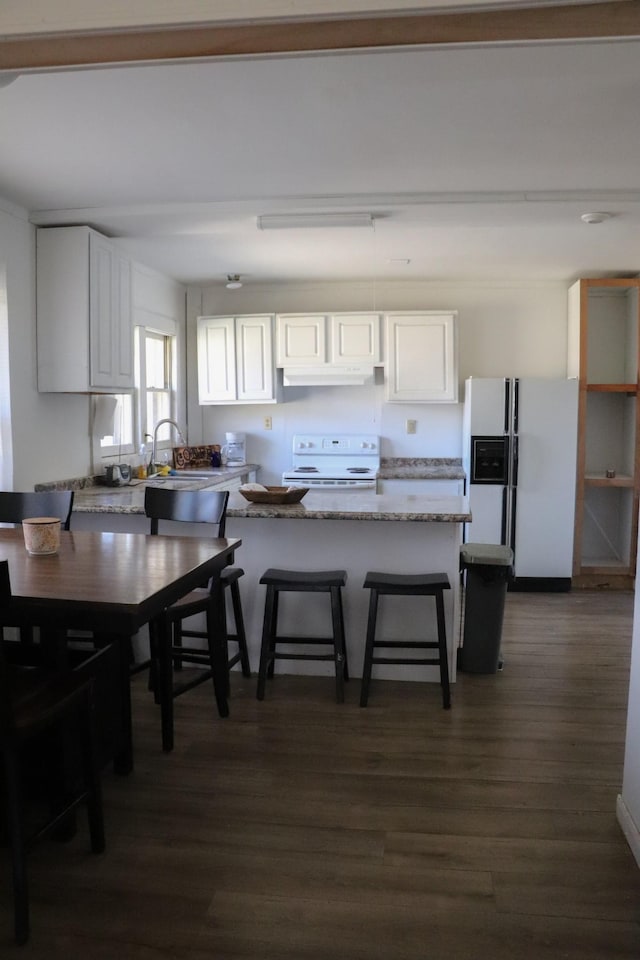 kitchen with light stone countertops, a breakfast bar, white cabinets, and white appliances