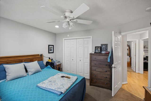 bedroom with a textured ceiling, a closet, ceiling fan, and carpet flooring