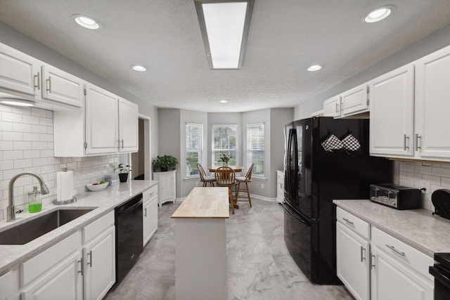 kitchen featuring wood counters, black appliances, sink, and white cabinets