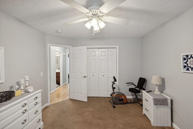 interior space featuring ceiling fan, light colored carpet, a closet, and a textured ceiling