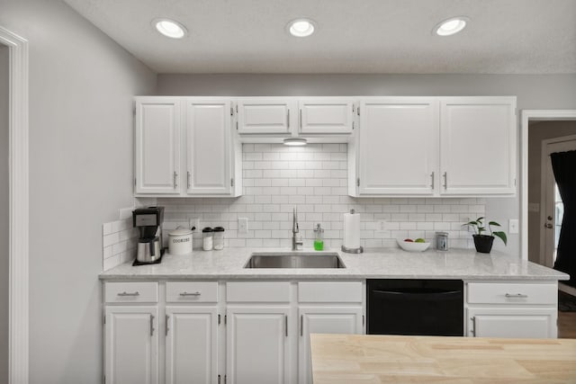 kitchen featuring tasteful backsplash, sink, white cabinets, and black dishwasher