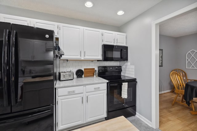 kitchen featuring decorative backsplash, white cabinets, light wood-type flooring, and black appliances