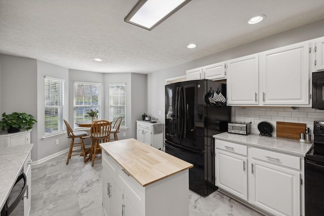 kitchen with tasteful backsplash, black appliances, white cabinets, and a kitchen island