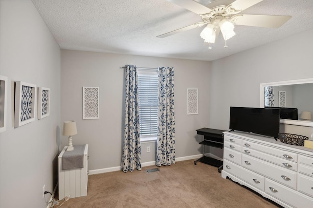 bedroom with ceiling fan, light carpet, and a textured ceiling