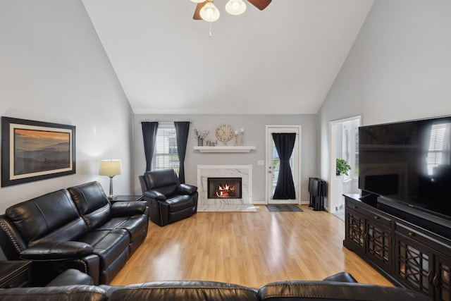 living room with high vaulted ceiling, a fireplace, light hardwood / wood-style floors, and ceiling fan