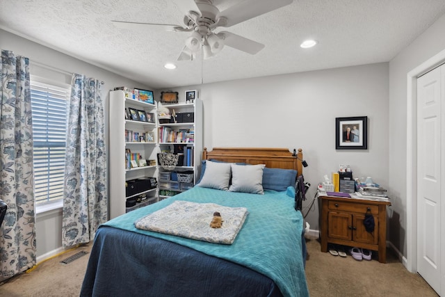 carpeted bedroom featuring multiple windows, ceiling fan, and a textured ceiling