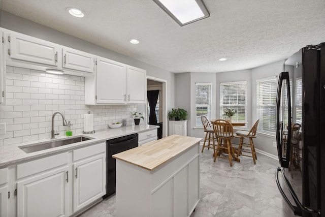 kitchen featuring a kitchen island, sink, white cabinets, backsplash, and black appliances