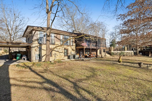 rear view of house featuring a carport, a yard, and central air condition unit