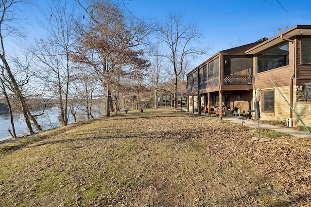 view of yard featuring a water view, a sunroom, and a patio area