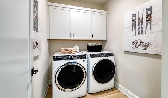 laundry area with cabinets, washer and clothes dryer, and light hardwood / wood-style floors