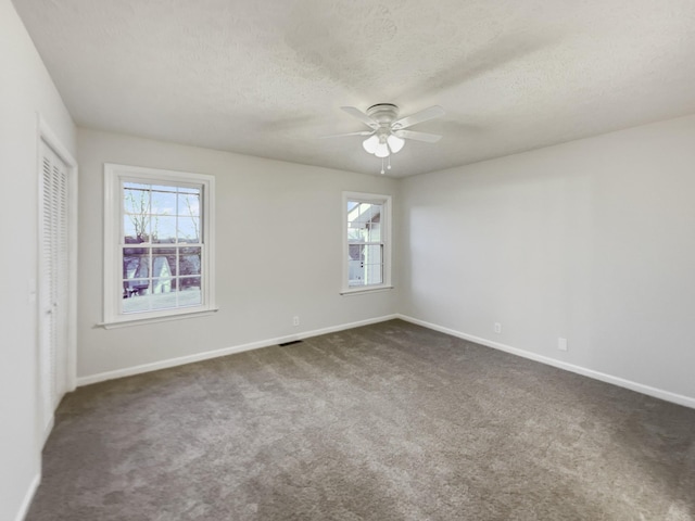 unfurnished room featuring ceiling fan, dark carpet, and a textured ceiling