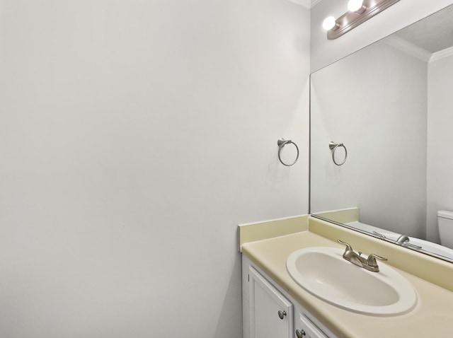 bathroom with crown molding, vanity, and toilet