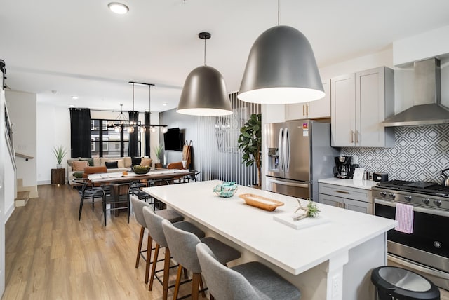 kitchen featuring decorative light fixtures, gray cabinetry, backsplash, stainless steel appliances, and light hardwood / wood-style flooring